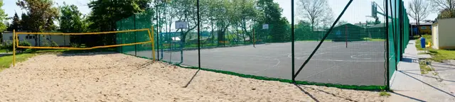 Piaszczysty kort do siatkówki plażowej sąsiadujący z ogrodzonym boiskiem wielofunkcyjnym