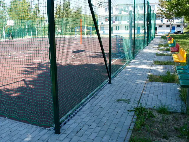 Kostka brukowa i kolorowe ławki dla zawodników przy ogrodzonym boisku wielofunkcyjnym