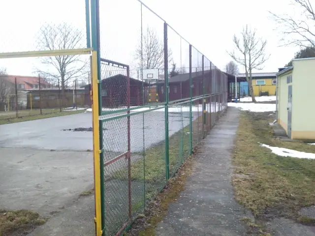 Istniejące stare boisko wielofunkcyjne z siatkowym ogrodzeniem przed przebudową w Sianożętach