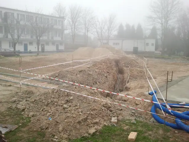 Wykop pod fundament z niebieskimi rurami osłonowymi na mglistym terenie ośrodka Neptun