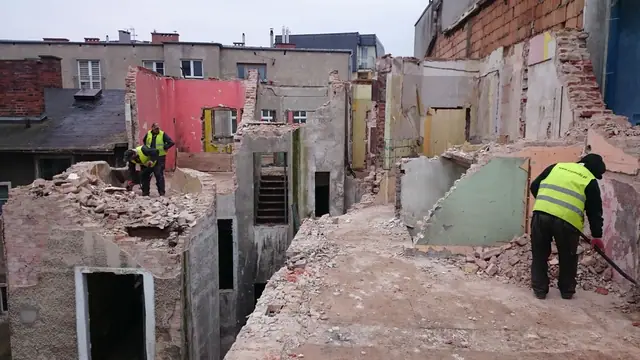 Dwaj pracownicy usuwają gruz z rozebranego piętra kamienicy przy ulicy Cichej