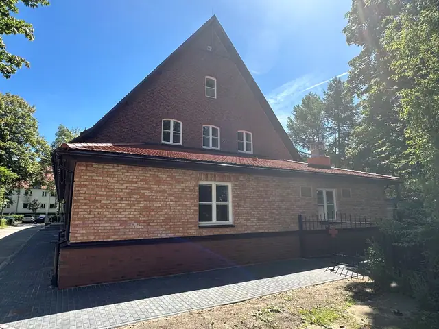 Szczytowa ściana budynku po modernizacji z nowymi oknami na tle bezchmurnego nieba