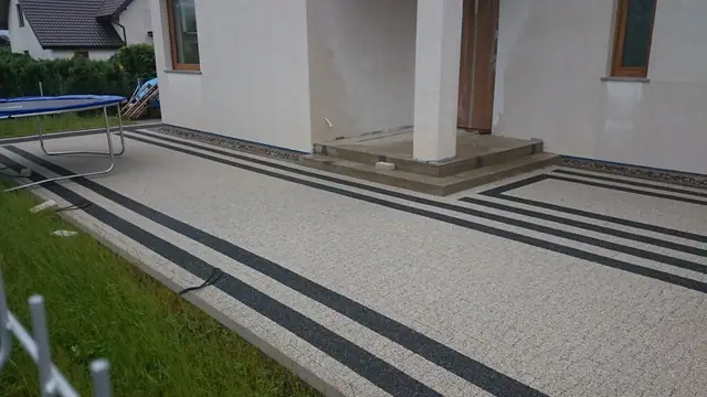 Taras z kostki granitowej w biało-czarne pasy przy wejściu do domu jednorodzinnego