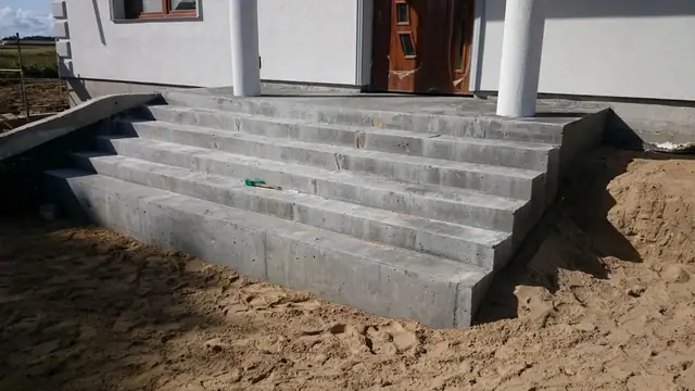 Świeżo wykonane betonowe schody zewnętrzne prowadzące do wejścia w budowanym domu