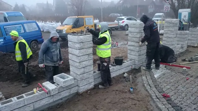 Ekipa SZYMETA wznosi rząd kamiennych słupków pod ogrodzenie przy domu jednorodzinnym