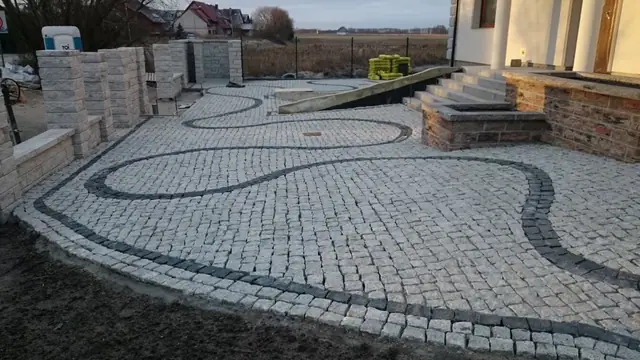 Zakończone prace na podwórku widziane od strony domu, esowaty wzór kostki i donice