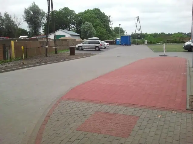 Nawierzchnia z powtórzonym czerwonym wzorem z kostki brukowej obok niewielkiego parkingu
