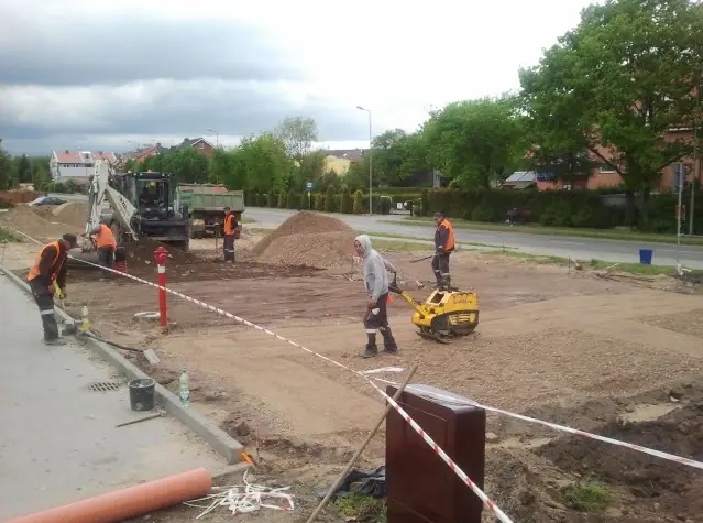 Ekipa zagęszcza grunt przy koparce i wywrotce w pobliżu hydrantu na terenie budowy