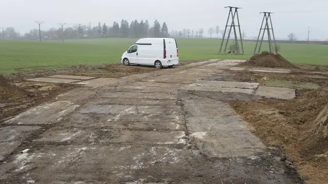 Droga techniczna z płyt betonowych prowadząca do stalowych masztów linii energetycznej