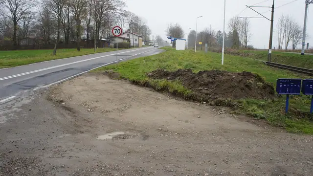 Droga z betonowych płyt prowadząca przez pole, widoczne uszkodzone fragmenty