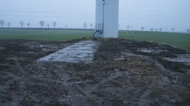 Rozjeżdżony, błotnisty plac manewrowy u podstawy turbiny wiatrowej w Tymieniu