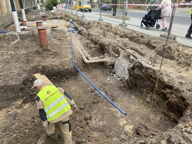 Pracownik SZYMETA zabezpiecza pomarańczowe rury instalacyjne w wykopie sieci zewnętrznych