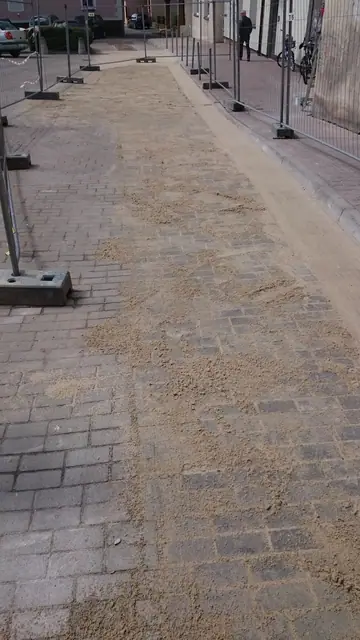 Fragment parkingu z ułożoną kostką brukową i piaskiem fugującym ogrodzony siatką