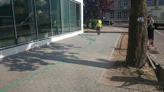 Geodezyjny sznur wyznacza linię przyszłej nawierzchni wzdłuż przeszklonej elewacji hotelu