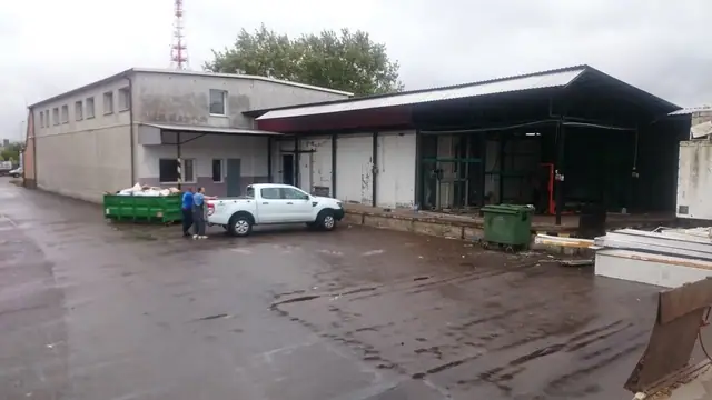 Hala magazynowa hurtowni z kontenerem na odpady i samochodem dostawczym przy wjeździe
