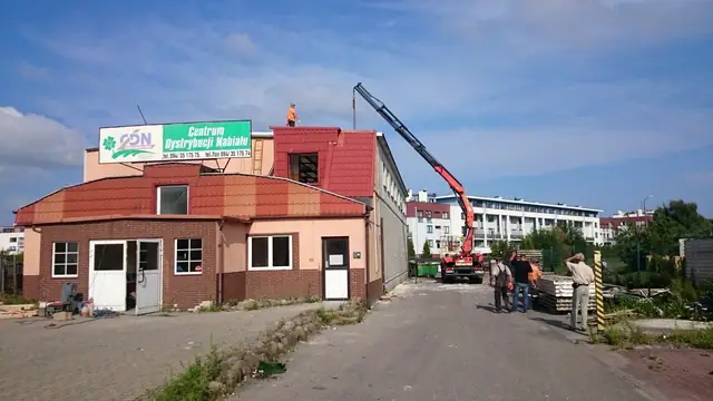 Żuraw HDS rozładowuje materiały przy budynku biurowym dawnej hurtowni nabiału