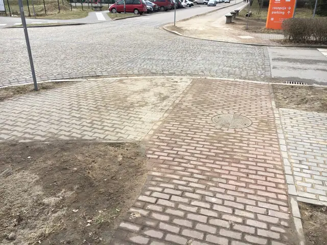 Skrzyżowanie chodników z kostki w różnych kolorach przy zjeździe na parking