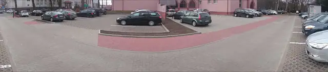 Widok na parking z czerwono-szarej kostki brukowej przed budynkiem kościoła