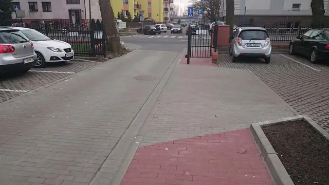 Wjazd z szarej i czerwonej kostki brukowej prowadzący do bramy przy kościele
