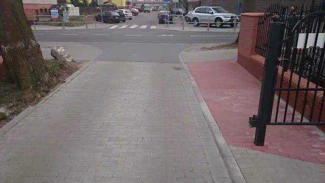 Wjazd z kostki brukowej przy metalowej bramie ogrodzeniowej terenu kościelnego