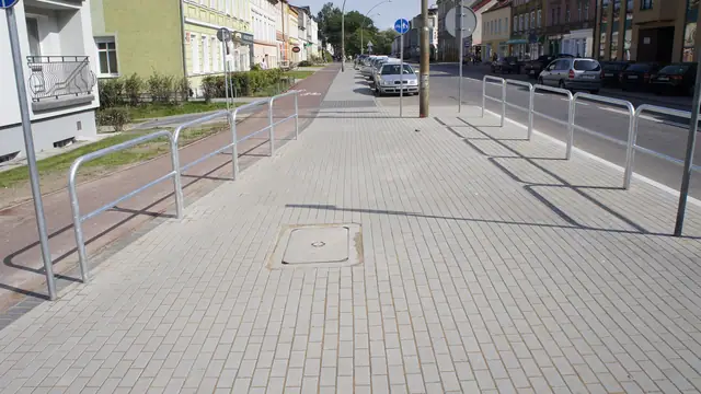 Chodnik z metalowymi barierkami i stojakami rowerowymi wzdłuż ulicy Zwycięstwa w Koszalinie
