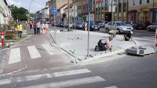 Robotnik układa kostkę brukową na skrzyżowaniu z przejściem dla pieszych w centrum Koszalina