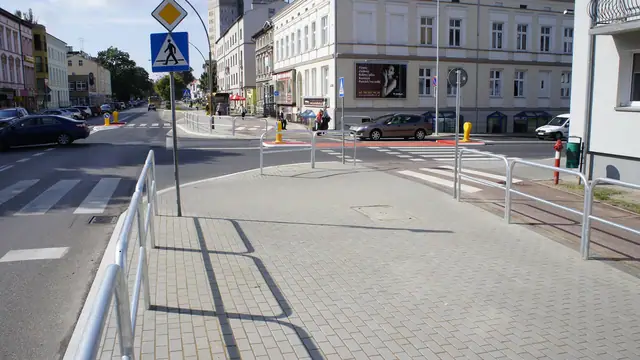 Wykończony chodnik z barierkami ochronnymi przy przejściu dla pieszych na skrzyżowaniu w Koszalinie