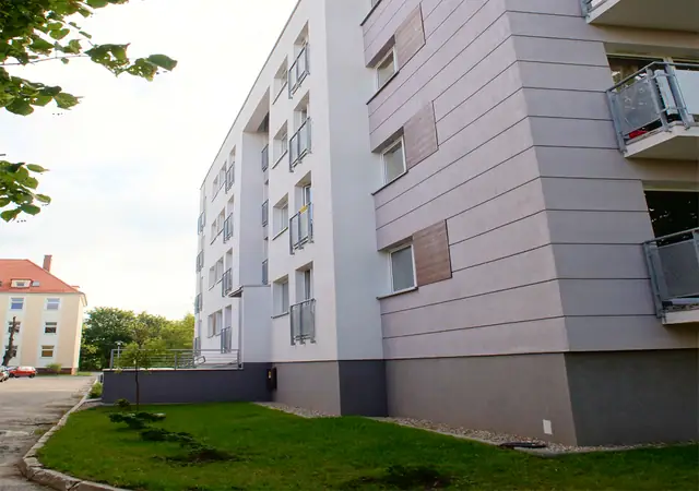 Narożnik budynku z elewacją w dwóch odcieniach szarości i balkonami