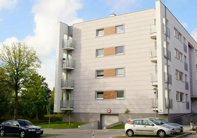 Wizualizacja elewacji budynku z balkonami i przeszkleniami, przed wejściem zaparkowane samochody