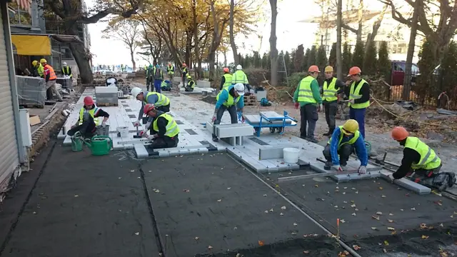 Robotnicy pracują nocą przy agregatach oświetleniowych podczas prac wykończeniowych placu przy molo w Kołobrzegu