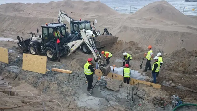 Robotnicy przy szalunkach betonują konstrukcję promenady w pobliżu wesołego miasteczka przy molo w Kołobrzegu