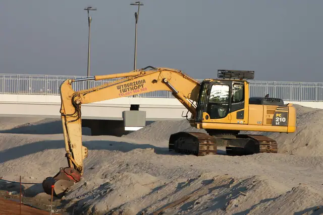 Koparka pracuje na moście nad estakadą podczas budowy konstrukcji betonowej przy molo w Kołobrzegu