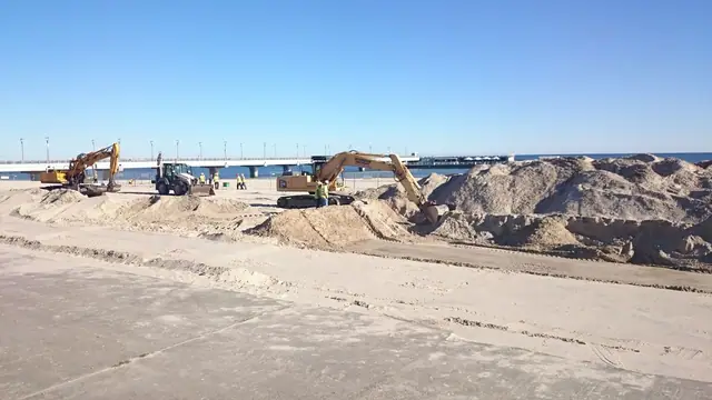 Koparki gąsienicowe formują wały piaszczyste na plaży w trakcie prac ziemnych przy molo w Kołobrzegu
