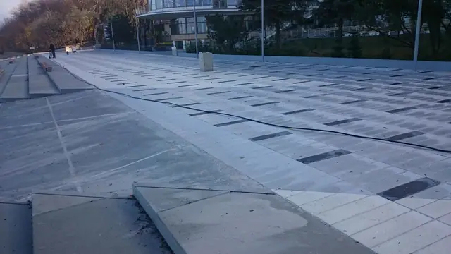 Widok z góry na drewniany pomost prowadzący przez plac w stronę hotelu przy molo w Kołobrzegu o zmierzchu