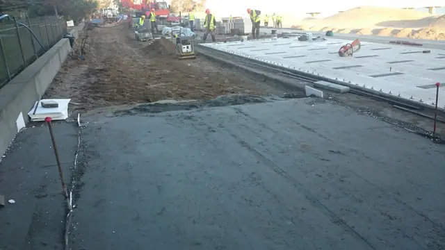 Nowo wybudowana promenada z prefabrykowanych płyt betonowych z robotnikami przy pracach wykończeniowych przy molo