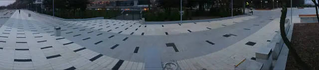 Promienisty wzór kamiennej nawierzchni przy schodach promenady przy molo w Kołobrzegu, zapalone latarnie uliczne
