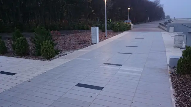 Szeroka ścieżka spacerowa wzdłuż wybrzeża przy molo w Kołobrzegu widziana o zmierzchu