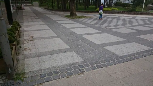 Wzór szachownicy z jasnych i ciemnych płyt na starej nawierzchni placu przy molo w Kołobrzegu przed przebudową