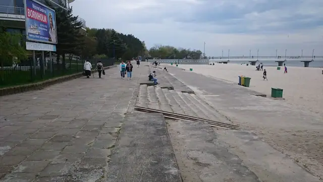 Przechodnie na starym chodniku z kostki przy straganie handlowym obok mola w Kołobrzegu przed modernizacją