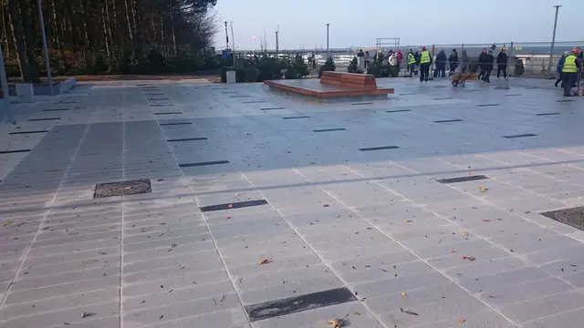 Widok z góry na drewniany pomost prowadzący przez ukończony plac w stronę morza przy molo w Kołobrzegu