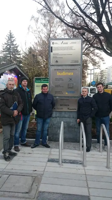 Wieczorny widok placu przy molo w Kołobrzegu w kierunku drzew i oświetlonych budynków w oddali