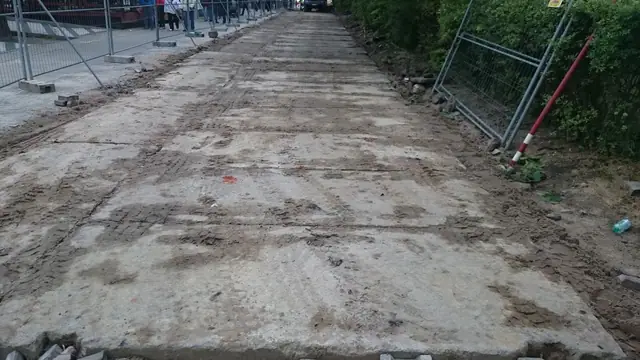 Wyrównany piaszczysty teren ze śladami po robotach ziemnych ogrodzony taśmą budowy przy molo w Kołobrzegu