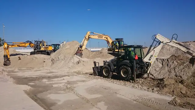 Koparko-ładowarki wyrównują piaszczysty teren pod przyszłą nawierzchnię promenady przy molo w Kołobrzegu