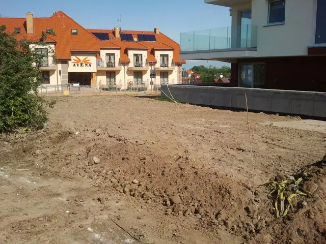 Wyrównana działka ziemna przed ukończonym budynkiem hotelu z pomarańczowym dachem