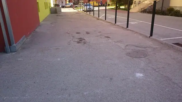 Zniszczona nawierzchnia asfaltowa parkingu przy budynku, stan przed remontem drogi