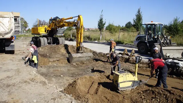Koparko-ładowarka i zagęszczarka gruntu na placu budowy przy wykopie instalacyjnym
