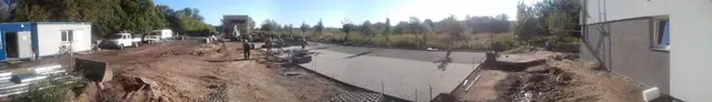 Świeżo wylany fragment nawierzchni betonowej wzdłuż elewacji budynku mieszkalnego