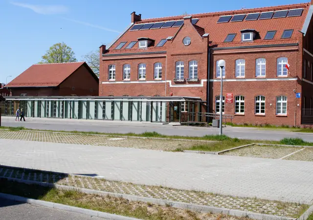 Ceglany budynek Morskiego Ośrodka Szkoleniowego w Kołobrzegu z placem utwardzonym kostką ażurową