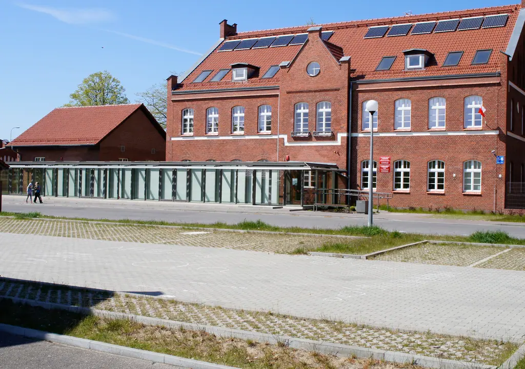 Ceglany budynek Morskiego Ośrodka Szkoleniowego w Kołobrzegu z placem utwardzonym kostką ażurową