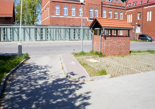 Chodnik prowadzący do murowanej bramki przy ceglanym budynku Morskiego Ośrodka Szkoleniowego w Kołobrzegu
